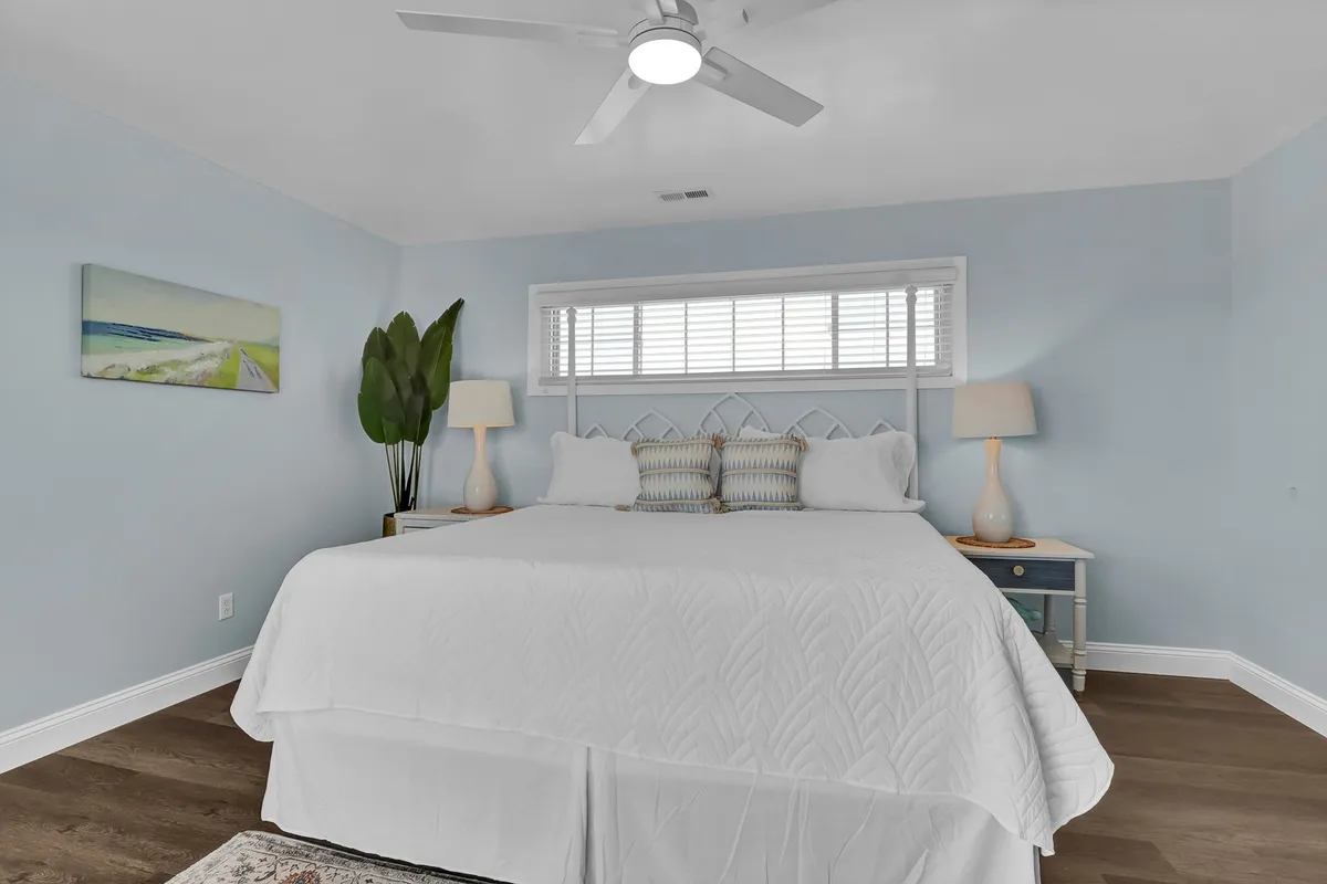 A third bedroom furnished with a comfortable bed, soft lighting from bedside lamps, a potted plant, and wall art. The room exudes serenity and privacy, offering a peaceful retreat for guests.