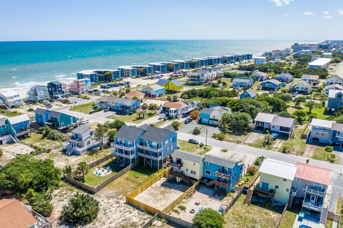 This vibrant exterior captures an ocean view framed by colorful houses and well-maintained gardens. The atmosphere is cheerful and lively, suggesting proximity to both the beach and local hotspots, with the potential for spontaneous group outings, festive gatherings, and leisure walks toward seafood restaurants.