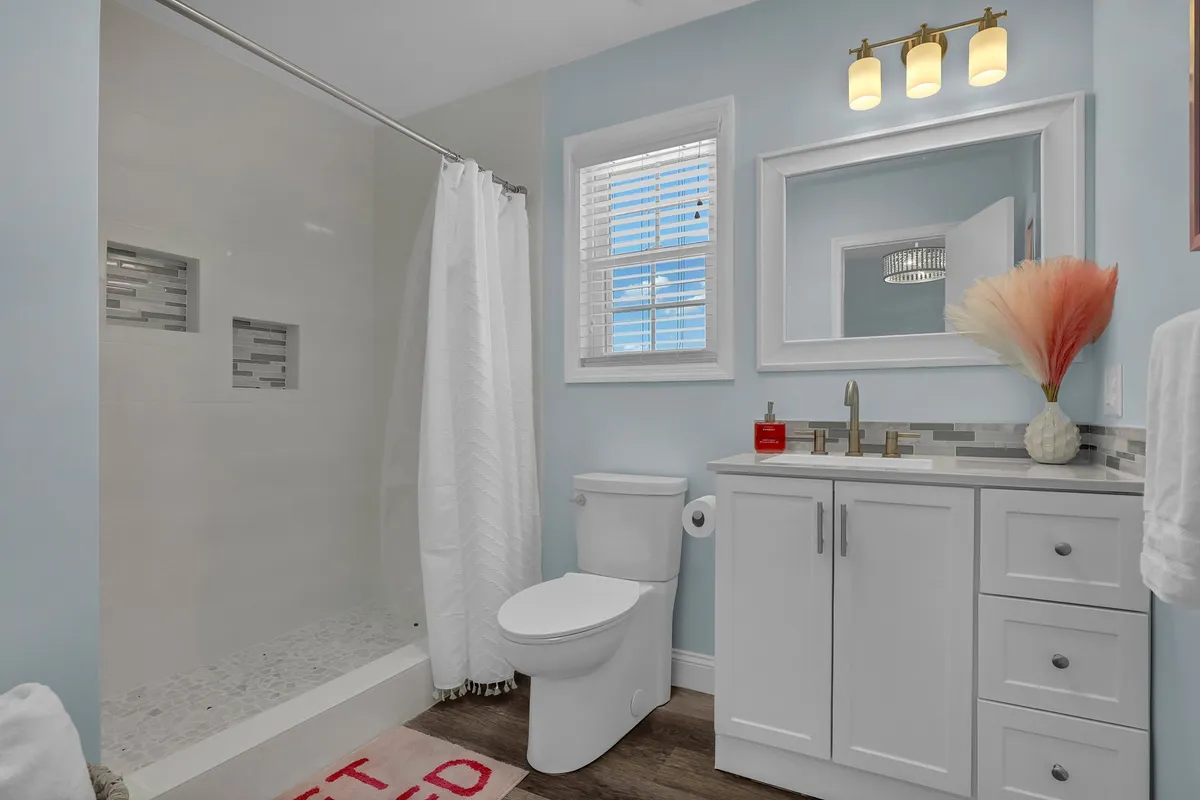 A modern bathroom featuring a sleek vanity with a sink, a decorative vase, and a spacious shower area. The space feels bright, inviting, and freshly updated—ideal for self-care and relaxation.