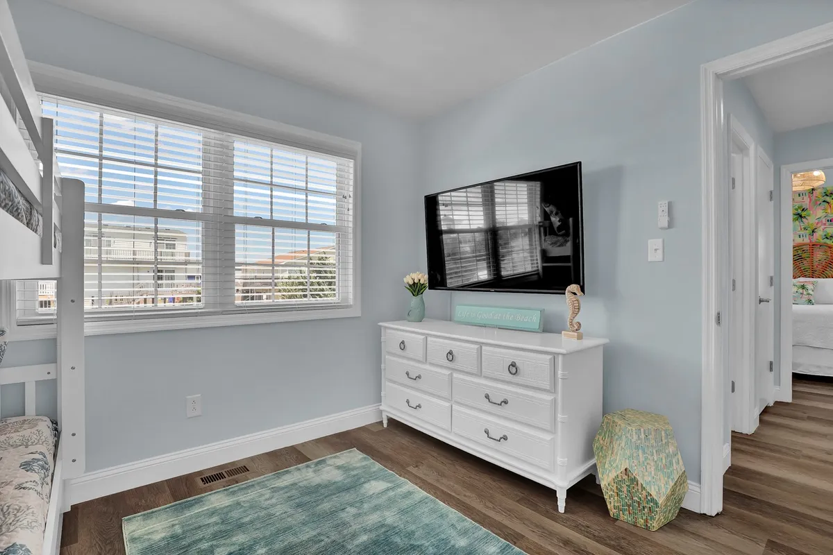 A cozy, kid-friendly bedroom featuring a bunk bed, television, dresser, and a decorative plant. The space is comfortable and playful, designed especially for young travelers to unwind after an active day.